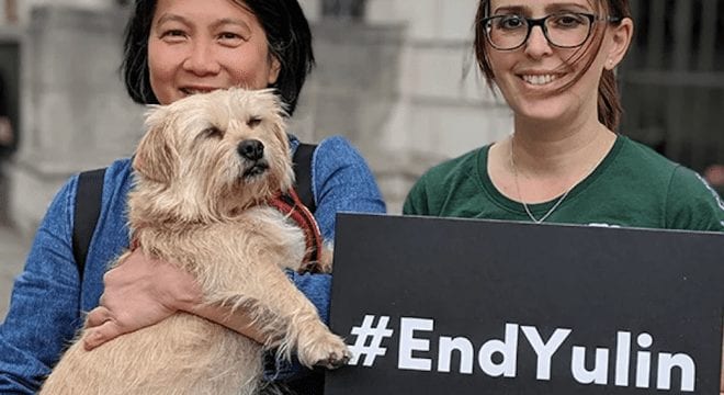 two girls holding a dog and banner against Yulin festival