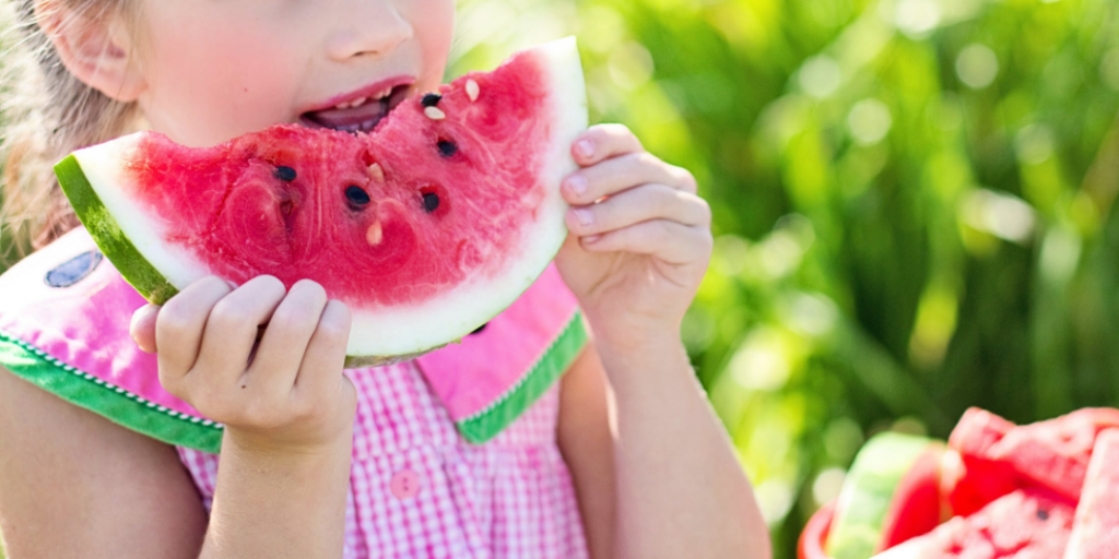 Kid eating watermelon showing Veganism is on the rise among UK schoolkids